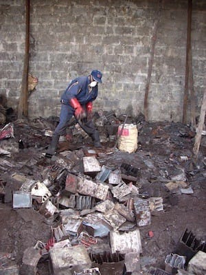 A worker sorts through used lead acid batteries, Kenya